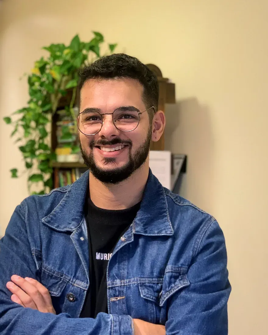 Psicólogo Felipe Santos sorrindo, de braços cruzados